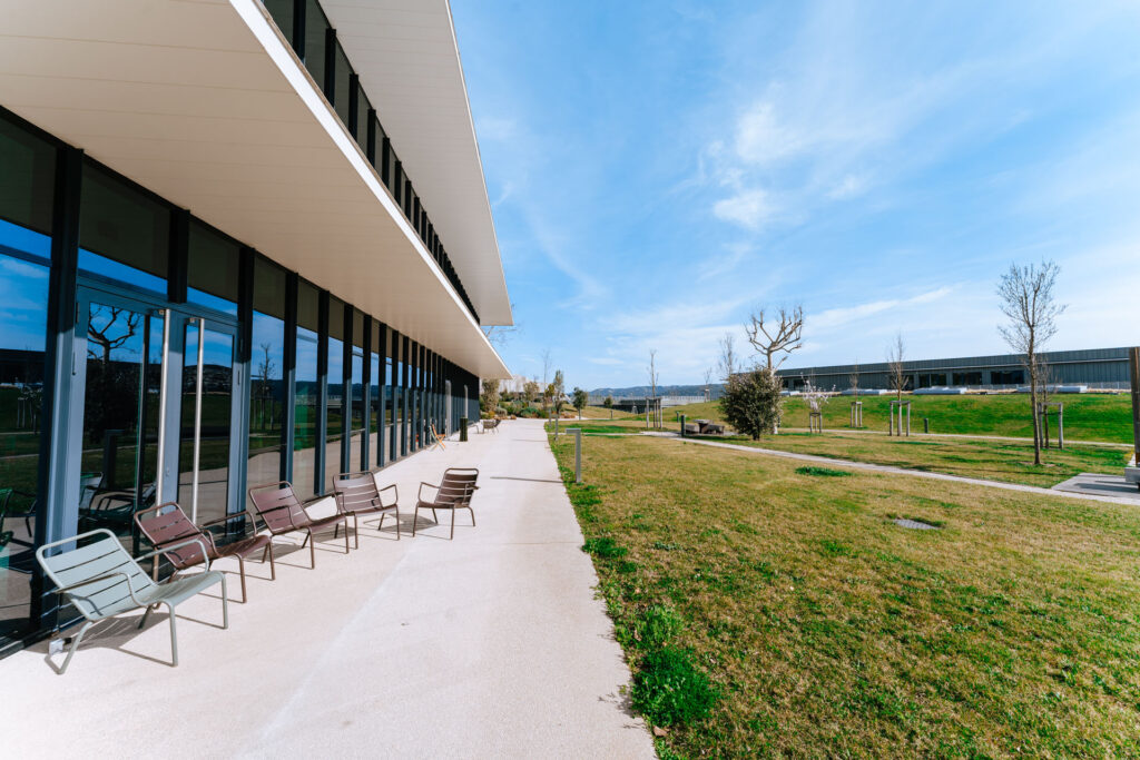 Modern office exterior with greenery at Voyage Privé HQ, showcasing a vibrant work environment.